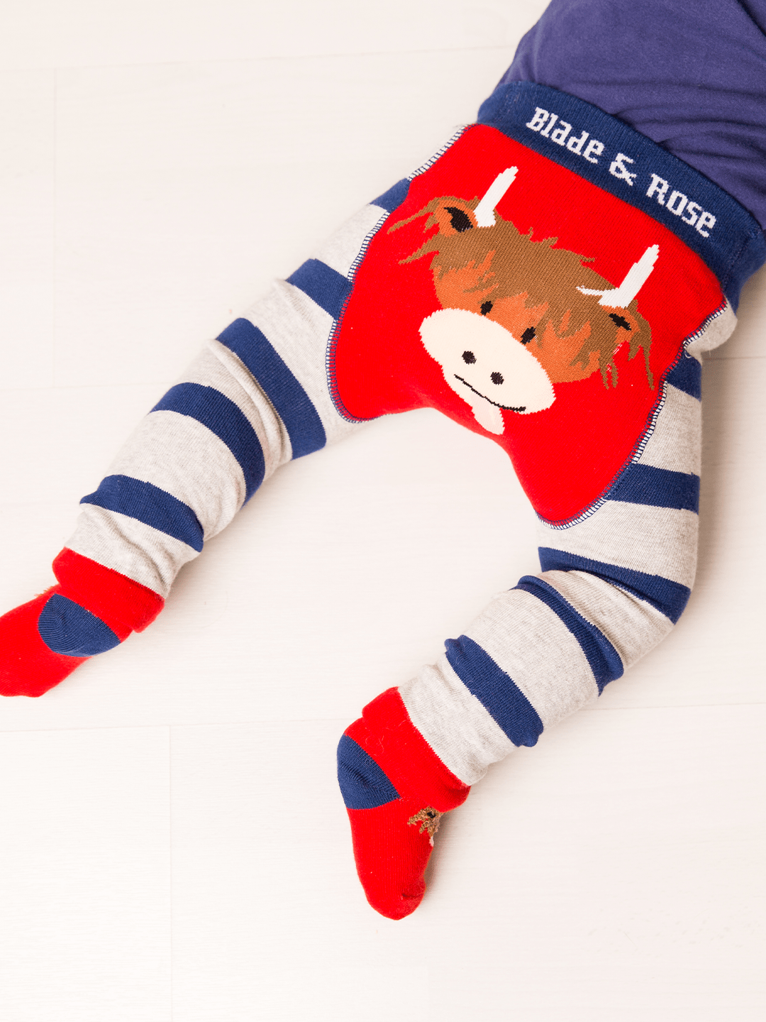 Children's leggings with cow design and striped pattern on a white background